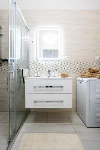 a white bathroom with a sink and a shower at Center Apartment Mlynska Kosice with private Parking in Košice
