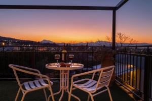 einen Tisch und zwei Stühle auf einem Balkon mit Blick auf den Sonnenuntergang in der Unterkunft Jo Marinis Rooms in Korinthos