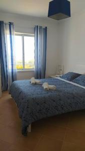 a bedroom with a bed with blue curtains and a window at Apartamento em Torreira - Nenúfares in Torreira