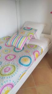 uma cama com uma colcha colorida e almofadas em Apartamento em Torreira - Nenúfares em Torreira