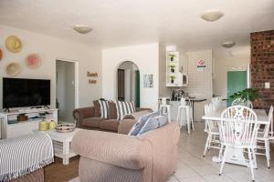 a living room with a couch and chairs and a kitchen at Paradise Self-Catering Units in Jeffreys Bay