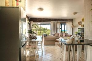 a kitchen and living room with a table and chairs at Paradise Self-Catering Units in Jeffreys Bay