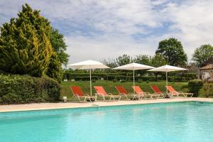een groep stoelen en parasols naast een zwembad bij La Chartreuse du Bignac - Teritoria in Saint-Nexans