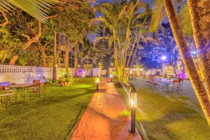 a garden with tables and chairs and palm trees at night at The Boho, Vagator Beach Goa Near Thalassa in Anjuna