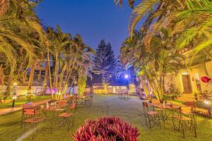 a group of tables and chairs in a courtyard with palm trees at The Boho, Vagator Beach Goa Near Thalassa in Anjuna