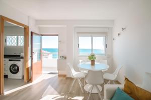 biała jadalnia ze stołem i krzesłami oraz oceanem w obiekcie Bonefish 2 Apartment w mieście Villajoyosa