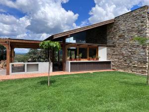 une maison avec une pelouse verte devant dans l'établissement Refúgio Morro Alto, à Delfinópolis
