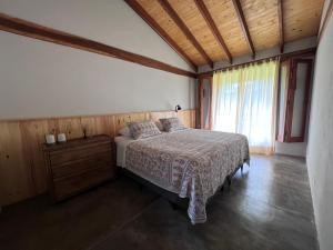 une chambre avec un lit et une grande fenêtre dans l'établissement Refúgio Morro Alto, à Delfinópolis