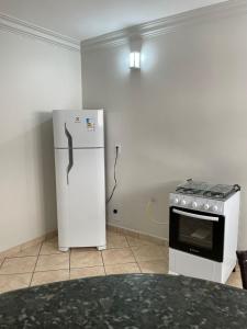 a kitchen with a white refrigerator and a stove at Apartamento aconchegante 1911 in Goiânia