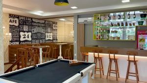 a pool table in front of a bar with stools at Eleganz Hostel & Suítes in Gramado