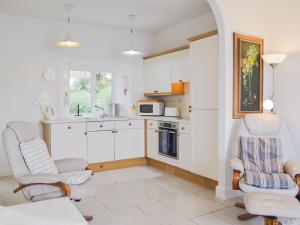 a kitchen with white cabinets and two chairs at Cliff Cottage - Uk43207 in Dale