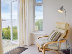 a chair in front of a window with a view of the ocean at Cliff Cottage - Uk43207 in Dale
