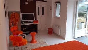 sala de estar con silla naranja y TV en Maison Ilaguinabaita 255 bis, en Urrugne