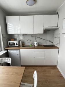 a kitchen with white cabinets and a table and a microwave at Apartament Stare Miasto Malbork in Malbork