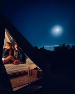 2 personnes assises sur un lit dans une tente la nuit dans l'établissement La Fattoria dei Sibillini, à Montemonaco