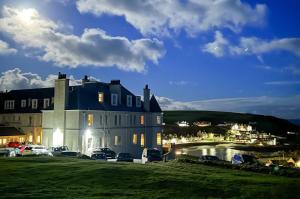 a large house with cars parked in front of it at The Portpatrick Hotel by Compass Hospitality in Portpatrick