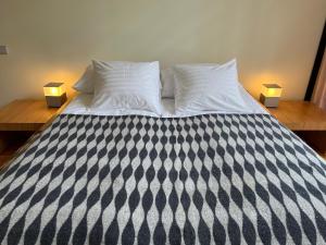 a bed with black and white sheets and two lamps at Holiday House Randu Pļavas in Salacgrīva