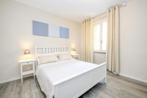 a white bedroom with a white bed and a window at Stella House in Desenzano del Garda