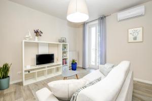 a white living room with a white couch and a tv at Stella House in Desenzano del Garda