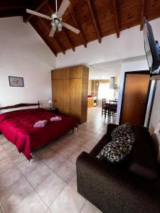 ein Schlafzimmer mit einem roten Bett und einem Sofa in der Unterkunft Virgen de las Nieves in San Martín de los Andes