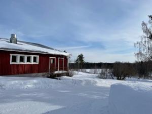 a red barn is covered in snow at Lamminmäen Juhla ja Peti in Joutsa