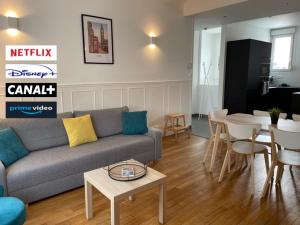ein Wohnzimmer mit einem Sofa und einem Tisch in der Unterkunft Le cinquante-deux appartement de Charme in Reims