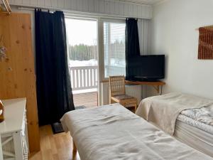 een slaapkamer met een bed, een televisie en een raam bij Lamminmäen Juhla ja Peti in Joutsa