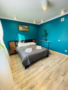 a bedroom with a bed and a blue wall at Apartamenty Happy & Relax in Bielsko-Biała