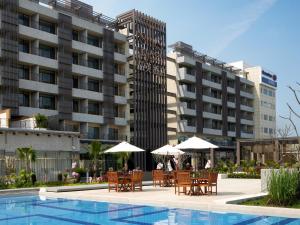 a hotel with tables and umbrellas next to a pool at Silks Place Yilan in Yilan City