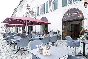 ein Restaurant mit Tischen, Stühlen und Sonnenschirmen in der Unterkunft Hotel Goldener Hirsch in Kaufbeuren