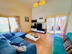 a living room with a blue couch and a table at Villa Irina in Caleta De Fuste