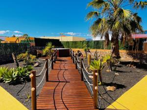 a wooden walkway in a garden with a palm tree at Villa Irina in Caleta De Fuste