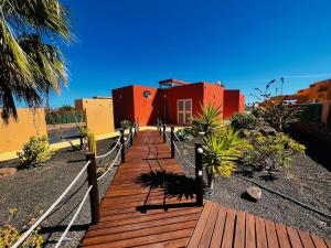 a wooden boardwalk leading to a house with red at Villa Irina in Caleta De Fuste