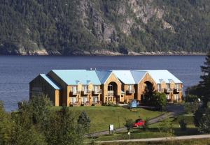 a large building with a lake in the background at Auberge des Battures in La Baie