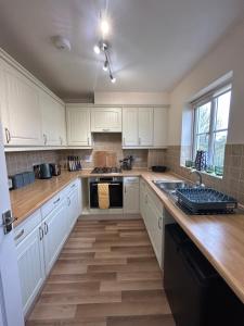a kitchen with white cabinets and a wooden floor at Spacious 5-bedroom nr Swanpool Beach - Falmouth in Falmouth
