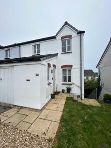 a white house with a garage at Spacious 5-bedroom nr Swanpool Beach - Falmouth in Falmouth