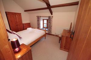a bedroom with two beds and a table and a window at Cilhendre Holiday Cottages - The Dairy in Swansea