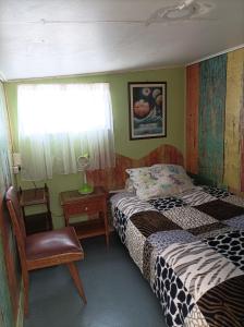 een slaapkamer met 2 bedden, een stoel en een raam bij Alojamiento familiar rey in Punta Arenas