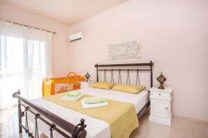 a bedroom with a bed with yellow sheets and a window at Villa Regina - Double Pool Paradise in Lachania