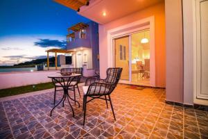 a patio with chairs and a table on a house at Villa Regina - Double Pool Paradise in Lachania