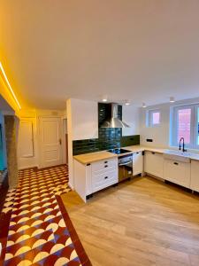 a large kitchen with white cabinets and a wooden floor at Apartamento PC in Torrelavega