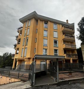 un edificio alto amarillo con una valla delante en La casa di Soddy, en Albano Laziale
