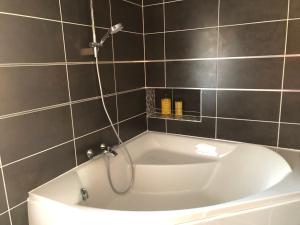 a white bath tub with a shower in a bathroom at L'escapade champenoise in Villers-Marmery
