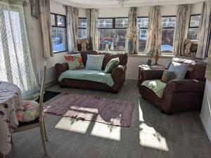 a living room with couches and a couch and windows at Ferny Roost Cabin. in Wrexham