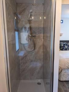a shower with a glass door in a bathroom at Ferny Roost Cabin. in Wrexham