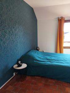 a bedroom with a blue bed and a table at Appartement dans village calme à 5 min des lacs in Mathaux