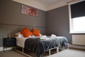 1 dormitorio con 1 cama con almohadas de color naranja en Blakeney House en Blakeney