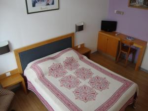 a bedroom with a bed and a table with a chair at Hôtel Au Petit Languedoc in Lourdes