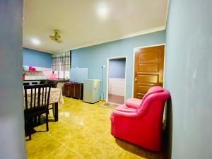 uma sala de estar com uma cadeira vermelha e uma cozinha em NABILA HOMESTAY em Pantai Cenang