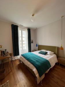 a bedroom with a bed and a table and a window at Maison d'hôtes Alma in Bordeaux
